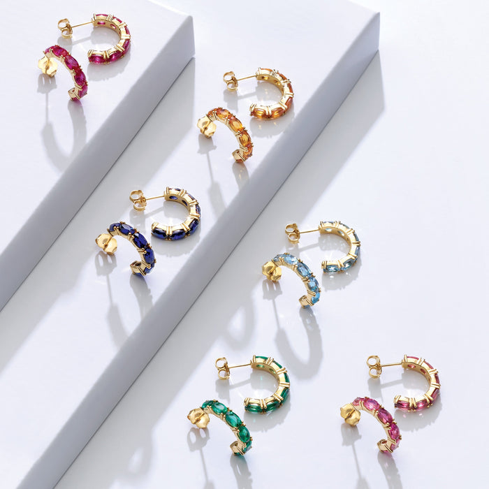 Colorful hoop earrings on a white surface