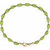 A gold tennis bracelet featuring a row of oval-cut green peridot gemstones, displayed on a clean white background.