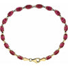 A yellow gold tennis bracelet featuring a series of oval-cut red ruby gemstones, displayed on a clean white background.