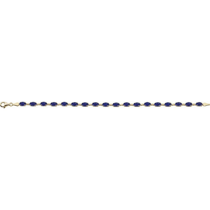 A gold tennis bracelet featuring a row of oval-cut dark blue sapphires, displayed horizontally against a solid white background.