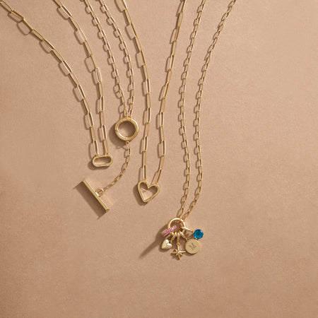 Gold charm necklaces with paperclip style links and different shaped charm bails.