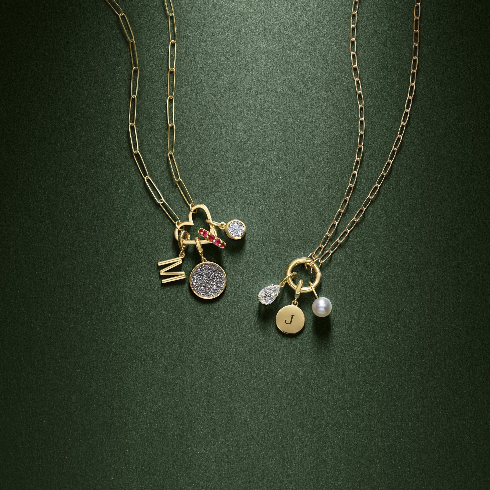 Two paperclip style gold charm necklaces with charm bails on a green background.