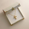 Gold necklace with a cross pendant in an open jewelry box on a light background