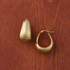 Puffed gold hoop earrings on a wooden surface