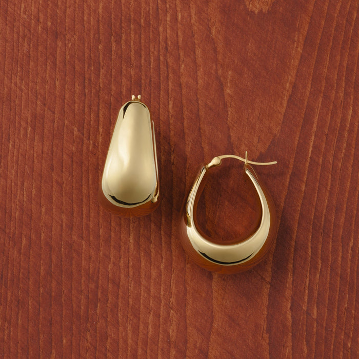 Puffed gold hoop earrings on a wooden surface