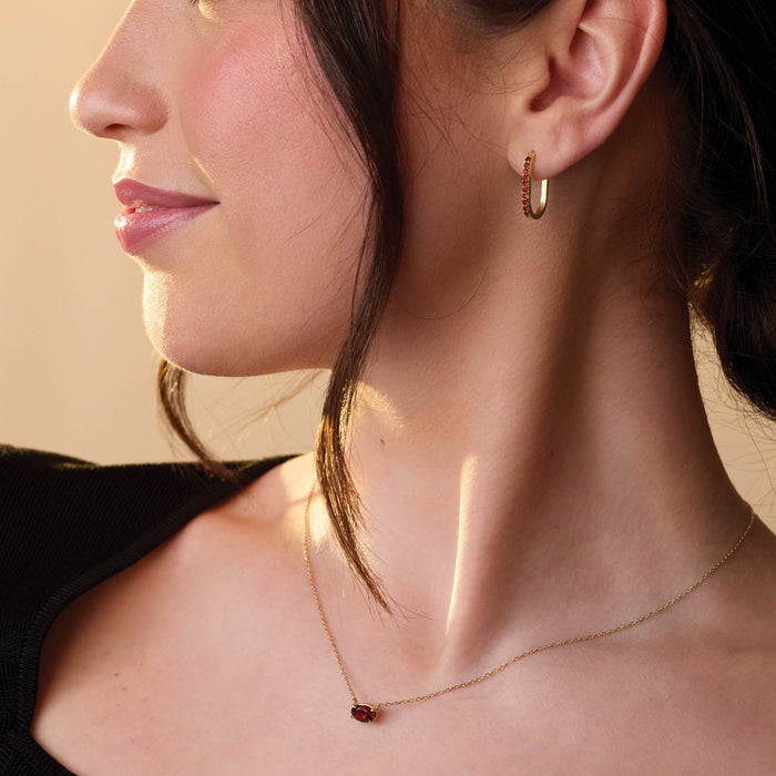 Woman wearing red stone gemstone pendant gold necklace