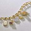 Gold charm bracelet with various charms on a light gray background