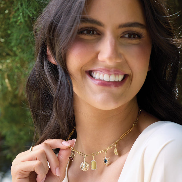 Woman wearing a gold necklace with charms outdoors