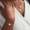 Aphrodite Coin Cable Chain Bolo Style Bracelet in 14K Yellow Gold on Model's Wrist with Other Goddess Necklaces