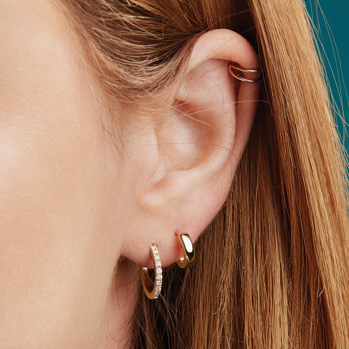 Model Wearing our Wear Everyday™ 9.5 MM Hinged Huggie Hoop Earrings in 14K Yellow Gold