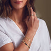 Model wearing arm stack of solid gold bracelets with our bangle bracelet