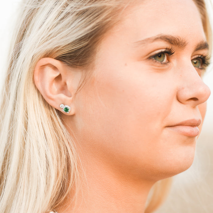 Model wearing lab-grown emerald diamond halo style stud earrings in sterling silver