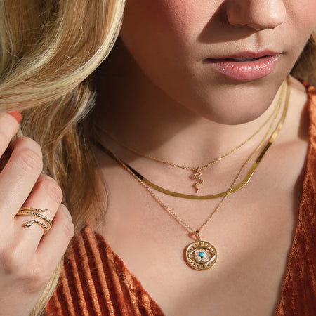 Model wearing our Garnet Spiral Snake 14K Yellow Gold Ring with Evil Eye Charm Necklace and Herringbone Necklace 